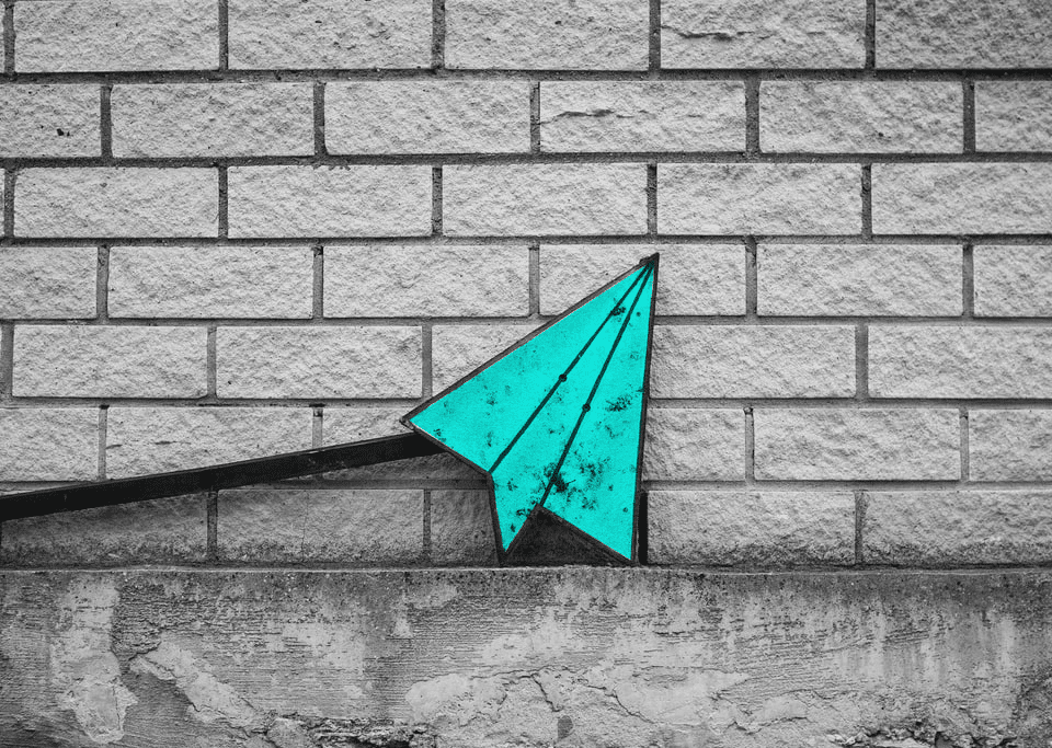 paper airplane leaning against brick wall